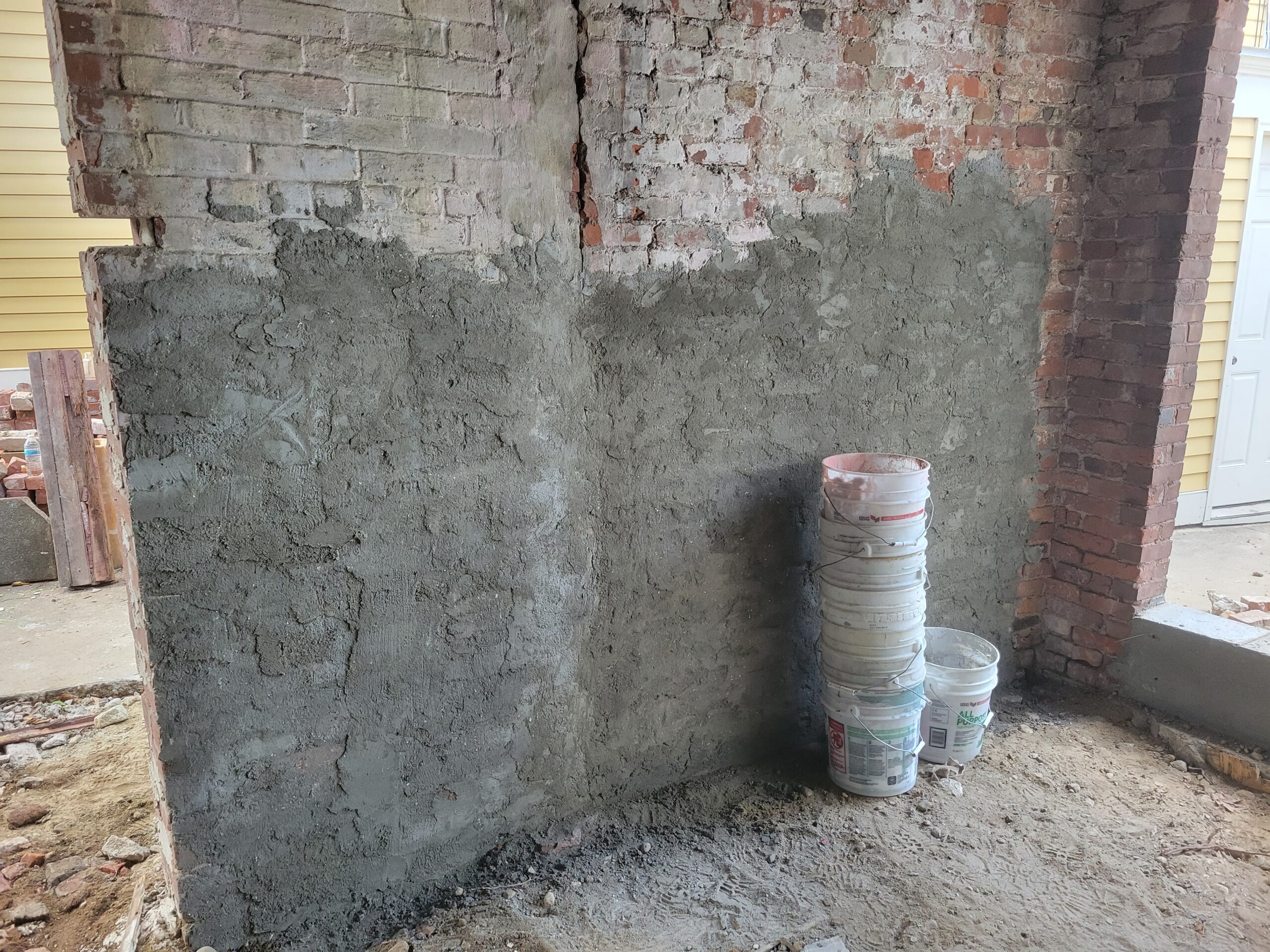 a brick wall is partially covered in a rough layer of cement