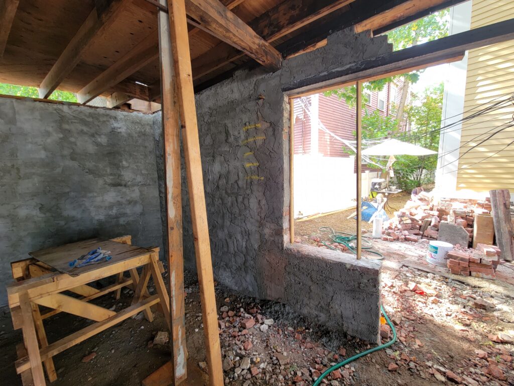 masonry repair in progress; wooden bracing holds up a beam, and several incomplete layers of brick are being constructed on top of a door frame